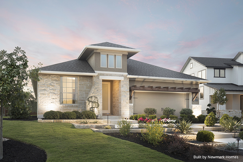 Exterior view of Masonwood home with white stone masonry, a dark grey roof, and a manicured lawn with a beautiful sunset in the background.